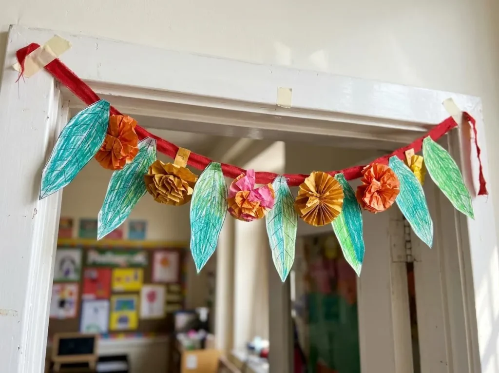 Paper toran of leaves and marigold flowers across a door