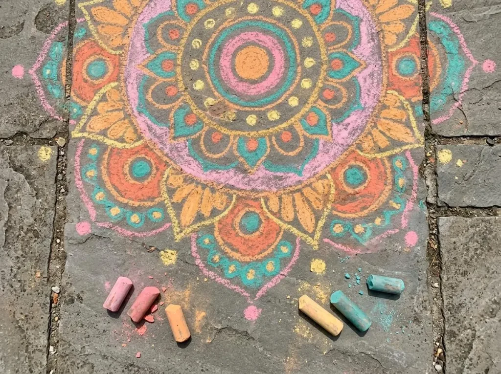 Colorful chalk rangoli drawn on a stone path